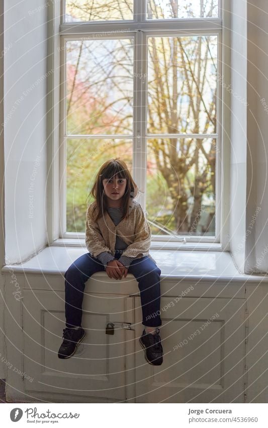 Mädchen, das auf einer Fensterbank sitzt, am Fenster Sitzen Kind Person Menschen Junge Porträt Kindheit wenig heimwärts im Innenbereich allein Glas Ausdruck