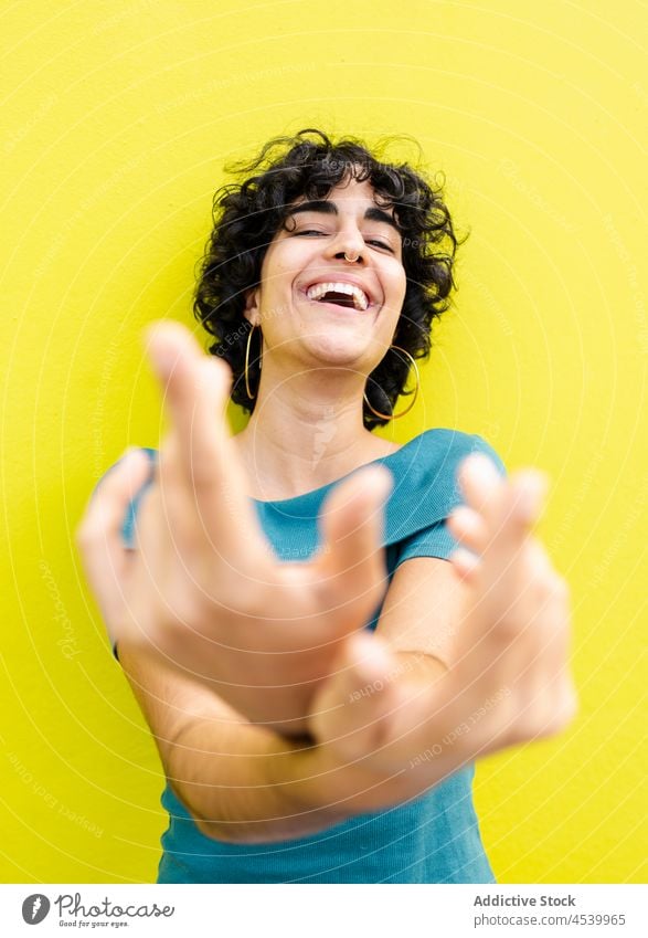 Glückliche Frau, die der Kamera ihre gekreuzten Hände entgegenstreckt Lachen Freude Spaß hell heiter expressiv farbenfroh sorgenfrei Optimist positiv Lächeln