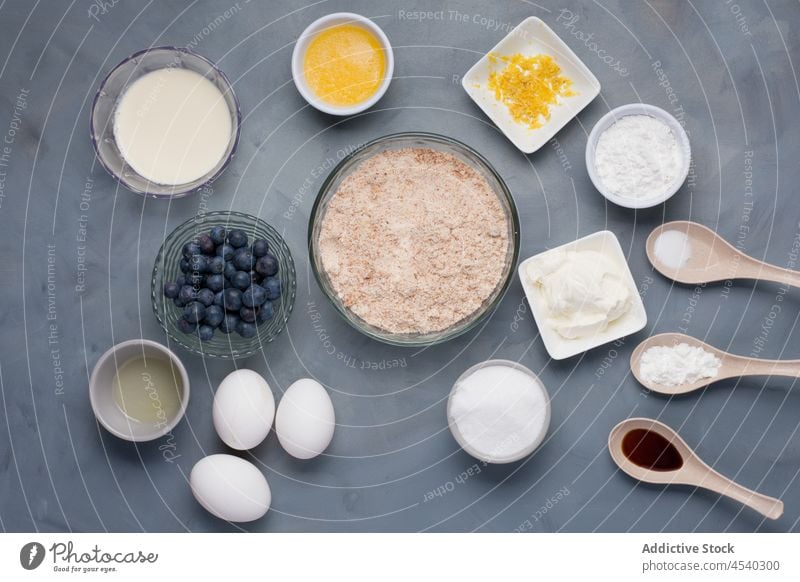 Set mit Zutaten in Schalen und Löffeln für die Zubereitung von Muffins Bestandteil Rezept Blaubeeren Mehl Zusammensetzung Gebäck vorbereiten Koch mischen melken