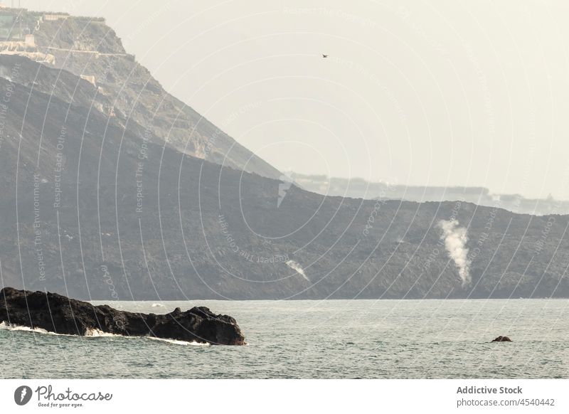 Felsige Berge, die das plätschernde Meer unter bewölktem Himmel umgeben MEER Berge u. Gebirge Natur Landschaft Meereslandschaft Insel malerisch felsig Klippe