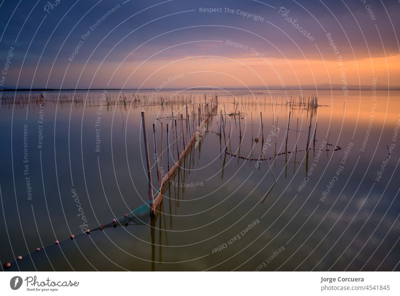 typisches Angelsystem mit Ruten und Stöcken, der Lagune von Valencia in Spanien. Schönes Bild mit einigen sehr interessanten Linien. In der Nähe von Sonnenuntergang Zeit mit einem beeindruckenden bewölkten Himmel und schöne Farben.