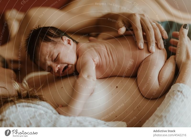 Anonymes nacktes Paar mit Baby kuschelnd auf dem Bett Familie neugeboren stillen Liebe Zusammensein Umarmen Partnerschaft schließen Ehefrau Ehemann Erwachsener