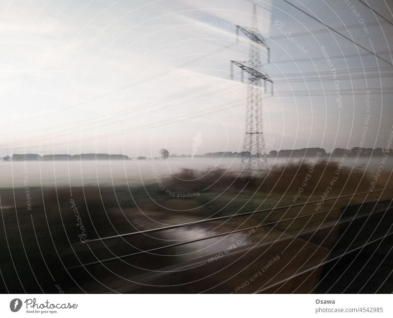 Zugfahrt Bahn Reise Fenster Geschwindigkeit Hochspannungsmast Gleise Schienen Morgen Nebel Landschaft schnell unscharf Bewegungsunschärfe Natur Verkehrswende