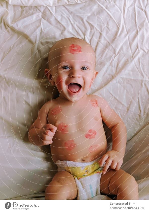 Baby auf dem Bett liegend mit Lippenstift Küsse alle über ihn Kuss Babyküsse Kindheit Liebe niedlich Porträt Kaukasier bezaubernd Familie Lifestyle