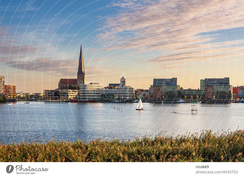 Blick über die Warnow auf die Hansestadt Rostock am Abend Fluss Stadthafen Mecklenburg-Vorpommern Kirche Petrikirche Schilf Herbst Boot Segelboot Reise Urlaub