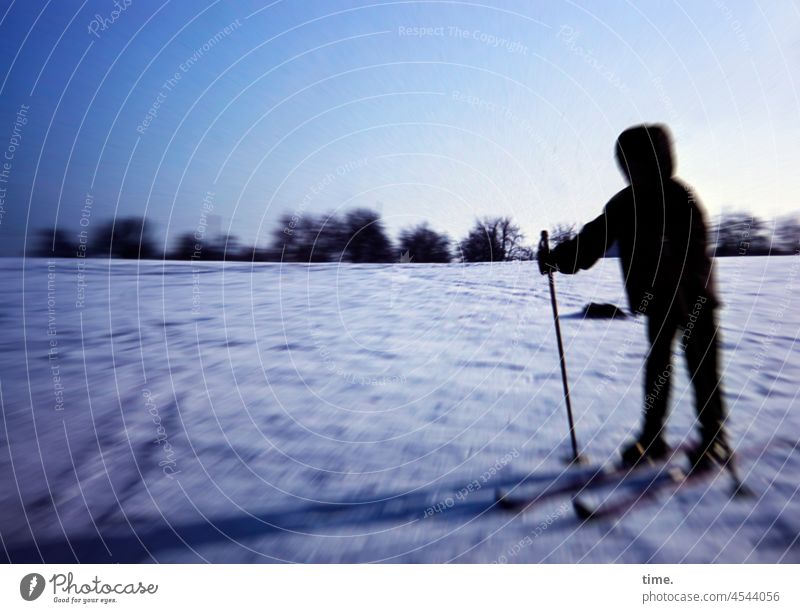 Raumgleiterin • Vermummtes Mädchen mit Skiern auf verschneiter Wiese im Abendlicht ski skisport wintersport schnee wiese abendlicht horizont anorak kapuze