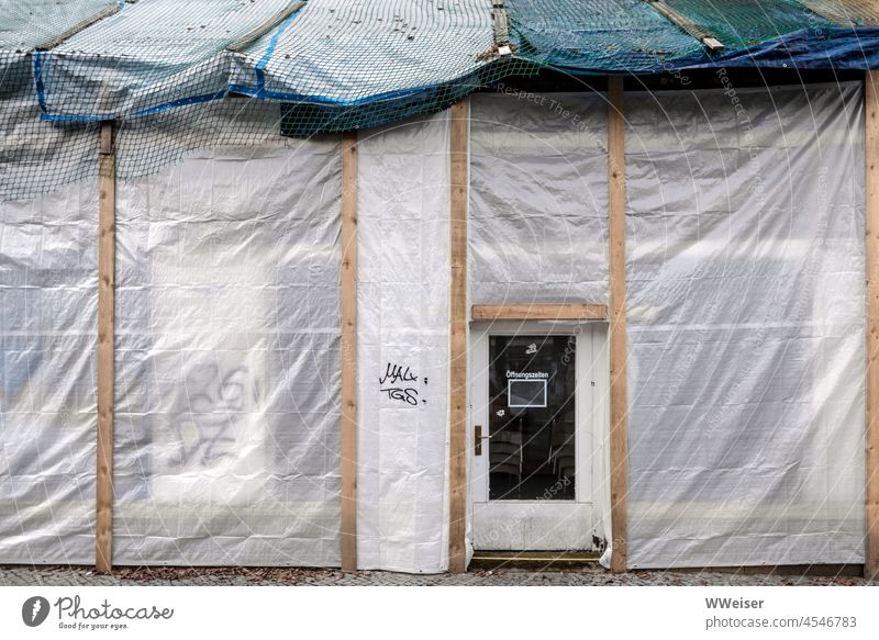 Hier gelten keine Öffnungszeiten mehr. Das Haus wird saniert, der Laden hat geschlossen Plane Gerüste Umbau Sanieren Fassade Straße Stadt Tür Eingang Geschäft