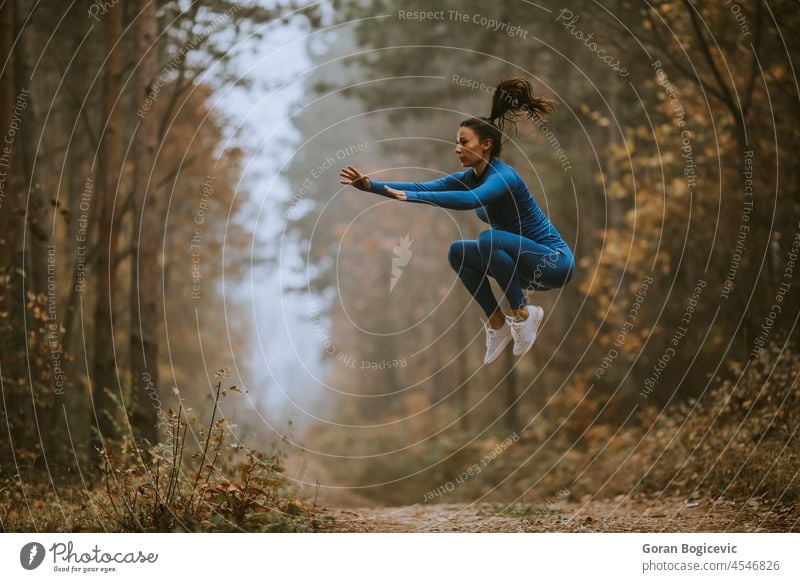 Junge Frau beim Hochsprung auf dem Waldweg im Herbst Aktion aktiv Aktivität Erwachsener Athlet sportlich attraktiv blau Kaukasier Land Ausdauer Energie Umwelt