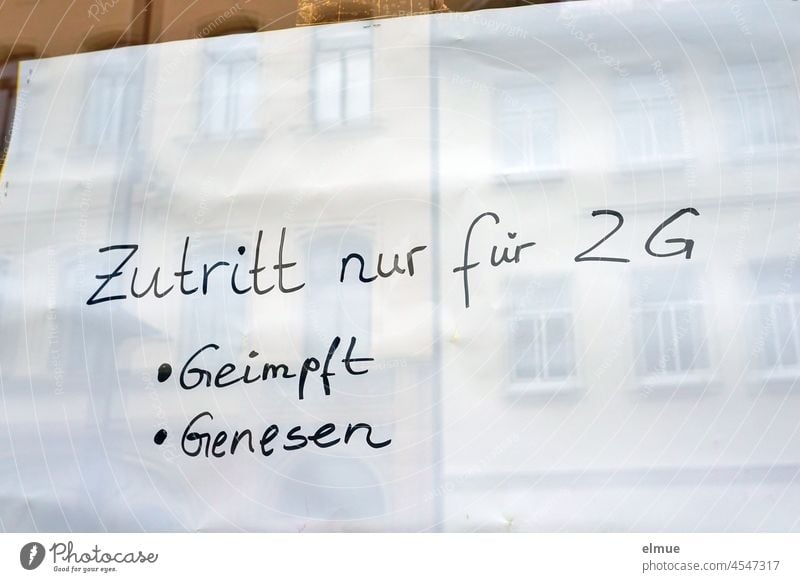 Zutritt nur für 2G - Geimpft - Genesen   steht in schwarz auf einem weißen Zettel hinter der Schaufensterscheibe / Coronakrise / Zutrittsbeschränkung