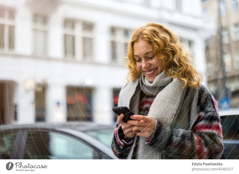 Junge Frau in der Stadt, die ihr Mobiltelefon überprüft eine Person Erwachsener schön lässig Mädchen Menschen Lifestyle urban Großstadt Straße attraktiv Porträt