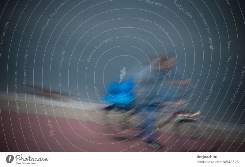 surreal  // Der Fahrradfahrer fährt mit einer wahnsinnigen Geschwindigkeit auf der Roten Fahrrad Spur. Auf dem Gepäckträger ist eine große blaue Tasche. fahren