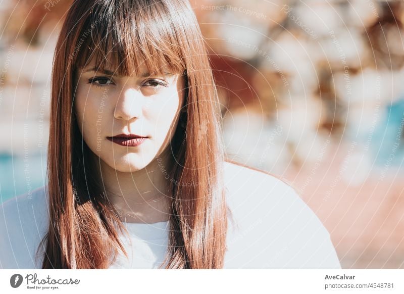 Close up Porträt einer jungen Frau im Park schaut ernst in die Kamera. Weißes Tshirt Kleidung leeren Raum. Redhead Schönheit Körper positiv Mädchen. Bunte Hintergrund Kopie Raum