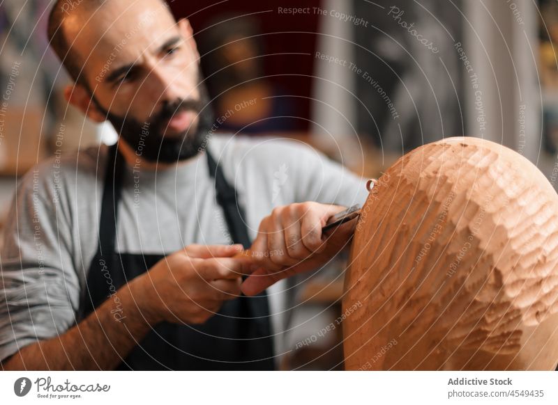 Konzentrierter Handwerker, der mit einem Meißel ein hölzernes Detail formt Zimmerer Beitel Form Holz Tischlerarbeit Werkstatt Handarbeit Holzarbeiten Instrument