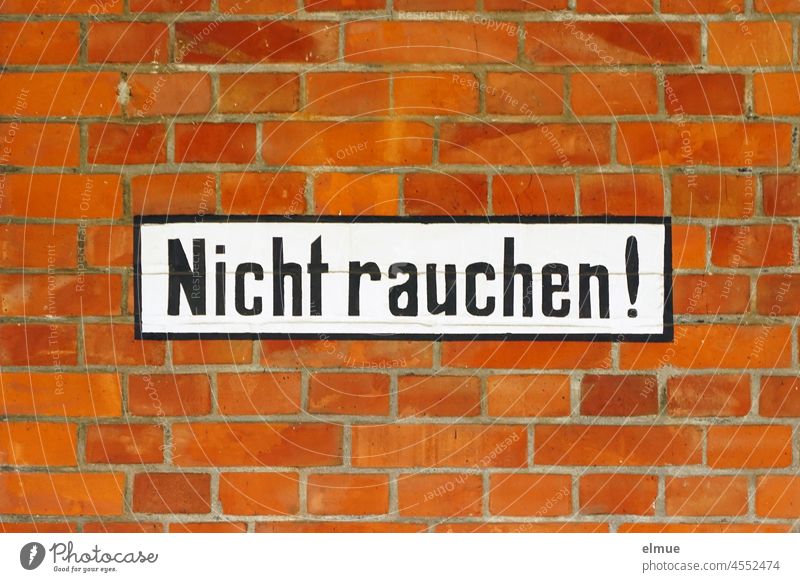 Nicht rauchen ! steht in schwarzen Buchstaben auf weißem Untergrund an einer roten Ziegelwand / Rauchverbot Schilder & Markierungen gute Vorsätze Nichtraucher