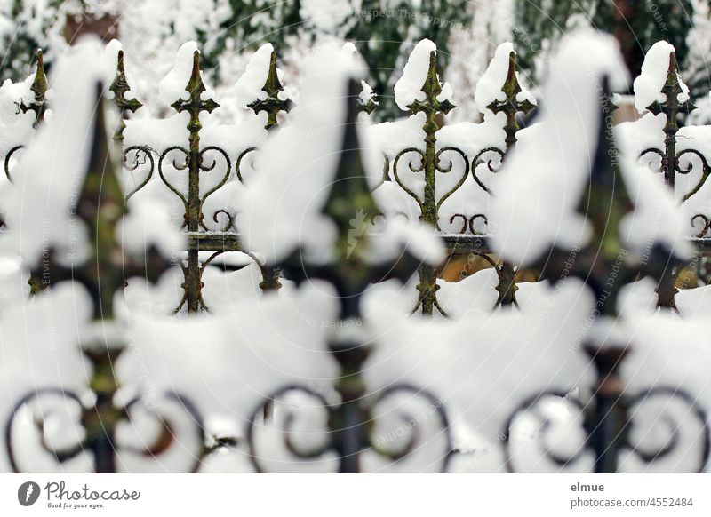 mit Schnee bedeckter alter schmiedeeiserner Friedhofszaun / Winter Zaun gusseisern Schmiedeeisen Zierzaun Zaunelement unscharf Tiefenschärfe lost places