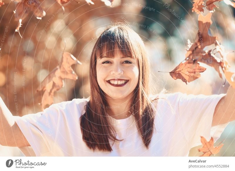 Glückliche junge Frau hat Spaß im Herbst forest.Woman portrait. Glückliches Mädchen in weißem Hemd und blauen Jeans spielt mit Blatt, Blick auf die Kamera und lächelnd.Close up Porträt im Herbst Park