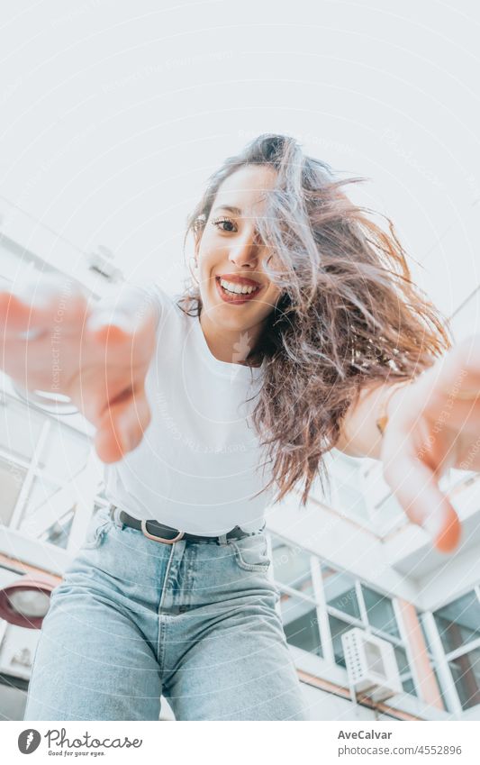 Urban Schuss eines modellierenden jungen afrikanischen Frau mit langen Haaren lächelnd und macht Posen zu Kamera. Stadt urbanes Konzept. Happy Day in der Stadt, weißes Hemd blaue Jeans. Modernes Outfit Styling. Straßenleben.