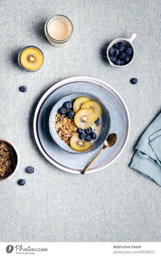 Frühstück mit einer Schale Müsli und gesunden Kiwis und Blaubeeren Morgen Lebensmittel Gesundheit Portion Tee Mahlzeit geschmackvoll Keramik lecker frisch