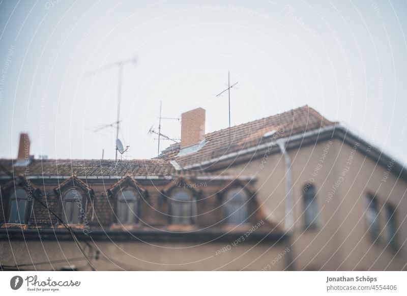 heruntergekommenes Haus mit Antennen und alten Dachziegeln Dachfenster rot Wohnen Miete Mietpreise Winter kalt Mehrfamilienhaus Altbau wohnen Fenster