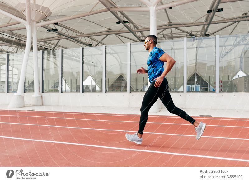 Fit Mann mit Sportkleidung und Sonnenbrille läuft auf dem Feldweg gutaussehend männlich ethnisch Afrikanisch junger Erwachsener Athlet Sportbekleidung rennen