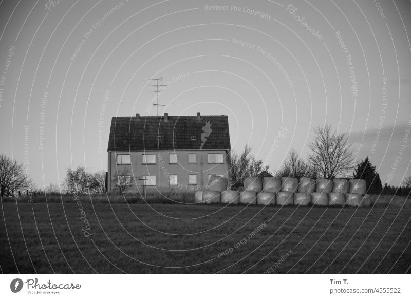 ein Mehrfamilienhaus am Feldrand Uckermark s/w Haus Strohballen Schwarzweißfoto Architektur Tag Außenaufnahme Menschenleer Gebäude Bauwerk Fassade Fenster