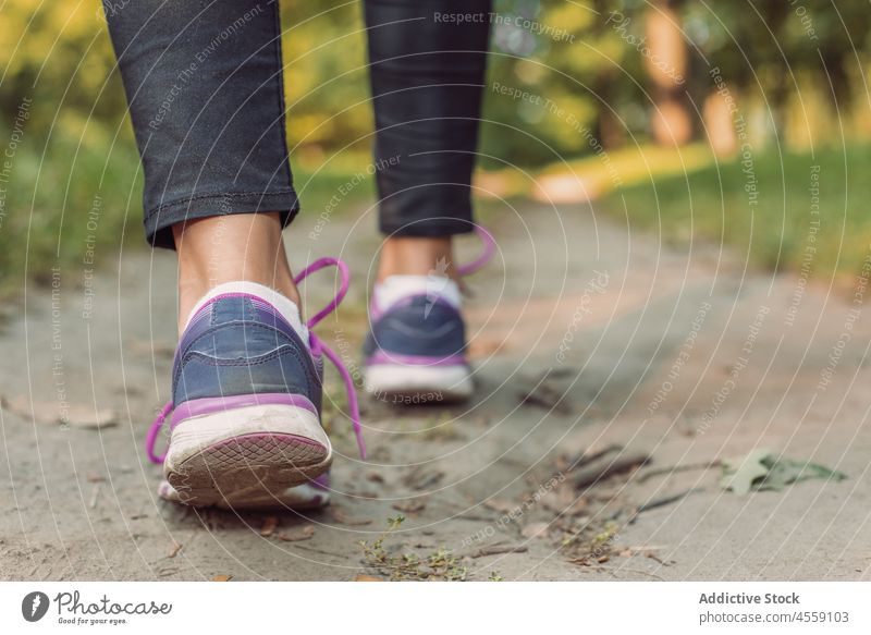 Crop Person Beine in Turnschuhen auf Boden Rasen im Wald Frau Park Spaziergang lässig Schuhe Jeanshose aktiv sich[Akk] entspannen schwarz Stiefel schlendern Fuß