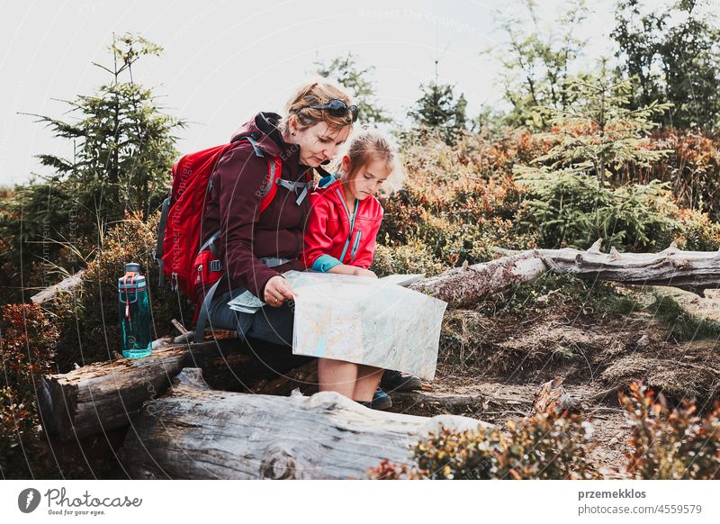 Familienausflug in den Bergen. Mutter und ihre kleine Tochter prüfen eine Karte, sitzen auf einem Baumstumpf während der Reise Kind Ausflug Urlaub Sommer