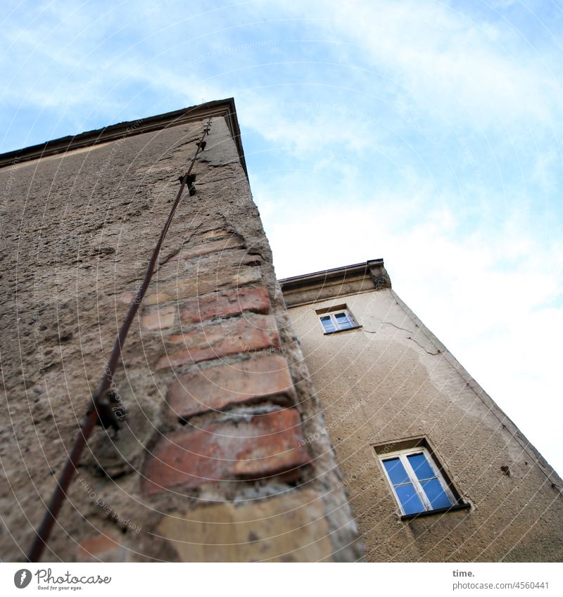 Halswirbelsäulentraining (43) • verwinkeltes Mauereck eines lost place mit altem Putz, freiliegenden Backsteinen, 2 Fenstern und 1 Blitzableiter unter leicht bewölktem blauen Himmel