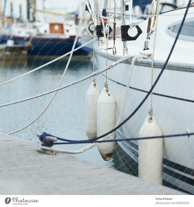 Fender, die zum Schutz zwischen einem Boot und dem Hafenbecken aufgehängt werden. Maritime Fender blau Holzplatte Bootfahren bouy Stoßstange Boje Nahaufnahme