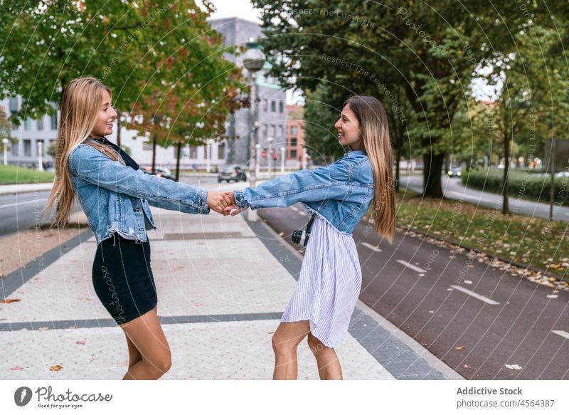 Zufriedene Frauen, die sich auf der Straße drehen Freund Fotoapparat sich im Kreise drehen sorgenfrei Spaß haben Zeit verbringen Hobby Großstadt positiv heiter