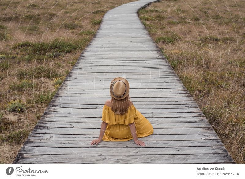 Anonyme Frau auf der Promenade im Grünen sitzend Düne Fußweg Natur Wiese Gras Landschaft corrubedo Galicia Weg Spanien hölzern Feld Sommer Kleid ländlich Urlaub