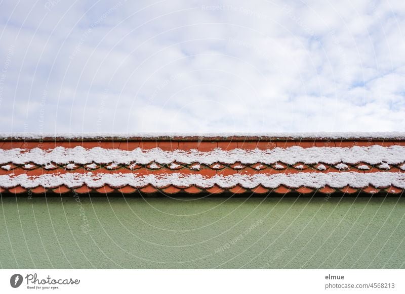 leicht verschneites schmales rotes Ziegeldach, grüne Hauswand und blauer Himmel mit weißen Wolken / Winter Dachziegel Schnee Farbe himmelblau Dekowolken Gebäude