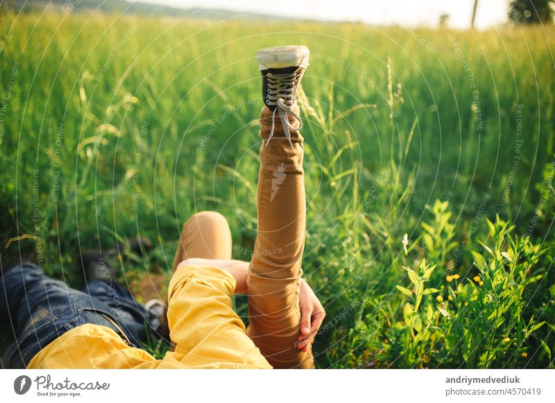 Frau und Mann haben Spaß im Freien. Verliebtes Hipster-Paar, das im Feld spazieren geht, sich küsst und die Hände hält, sich umarmt, im Gras liegt und im Sommer bei Sonnenuntergang die Beine hochlegt. valentines day