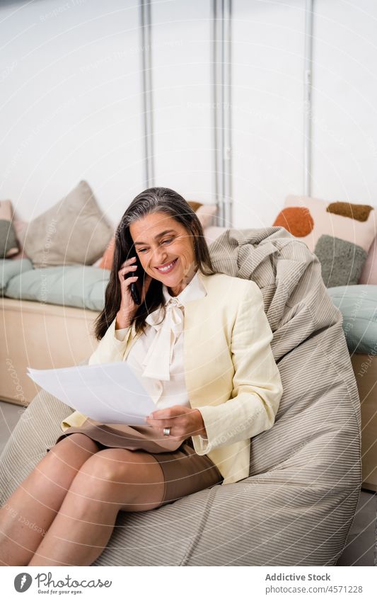 Fröhliche Frau mit Dokumenten beim Telefonieren Smartphone Telefonanruf Gespräch Schriftstück Papierkram Arbeit Büro Arbeiter analysieren diskutieren