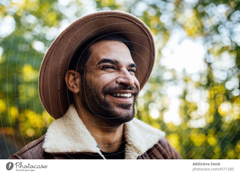 Glücklicher Hipster im Wald mit grünen Bäumen stehend Mann Baum Natur Stil Hain Abenteuer Ausflug Erholung Wälder Freizeit Outfit trendy Hut Sommer anhaben