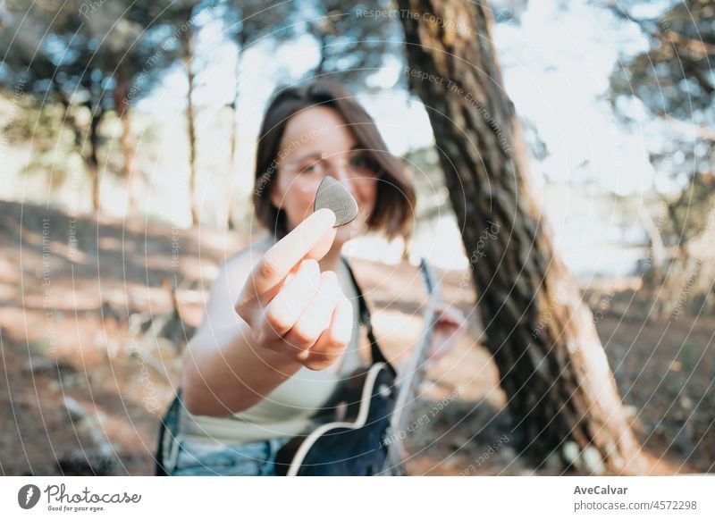 Junge Hipster Frau spielt die Gitarre lächelnd außerhalb des Waldes Park der Stadt. Viel Spaß beim Lernen einer neuen Fähigkeit, Musik spielen saisonalen Stil. Junge kurze Haare Mädchen. Kopieren Raum