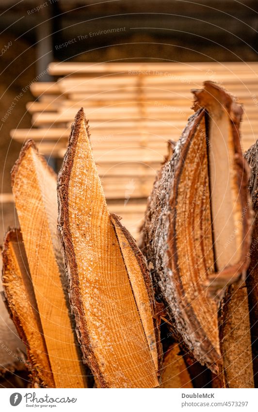 Unsortierte Holzlatten mit Baumrinde im Vordergrund und sortierte Holzsbretter im Hintergrund Stapel Haufen Stapelung Sammlung hölzern Abholzung