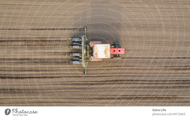 Luftaufnahme eines Traktors, der eine Sämaschine über ein landwirtschaftliches Feld zieht, Ackerland oben Ackerbau anbaufähig Müsli Mais Kornfeld Land Ernte