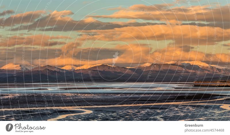 Letztes Licht auf der schneebedeckten Scafell-Bergkette links und Dow Crag, Coniston Old Man und Wetherlam ganz rechts, mit Blick über die Duddon-Mündung von Roanhead an der Cumbrian Coast.