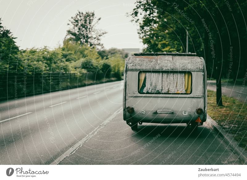 Alter Wohnwagen mit weißen Gardinen steht am Straßenrand Camping alt grün Perspektive Roadtrip Wohnmobil Fenster Ferien & Urlaub & Reisen Freiheit Mobilität