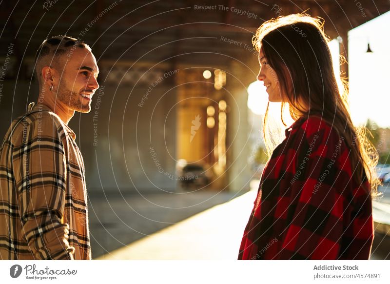 Junge lächelnde Freunde stehen unter einer Brücke bei Sonnenschein Frau Mann expressiv Sitzung sorgenfrei Freundschaft Sonnenuntergang cool tausendjährig