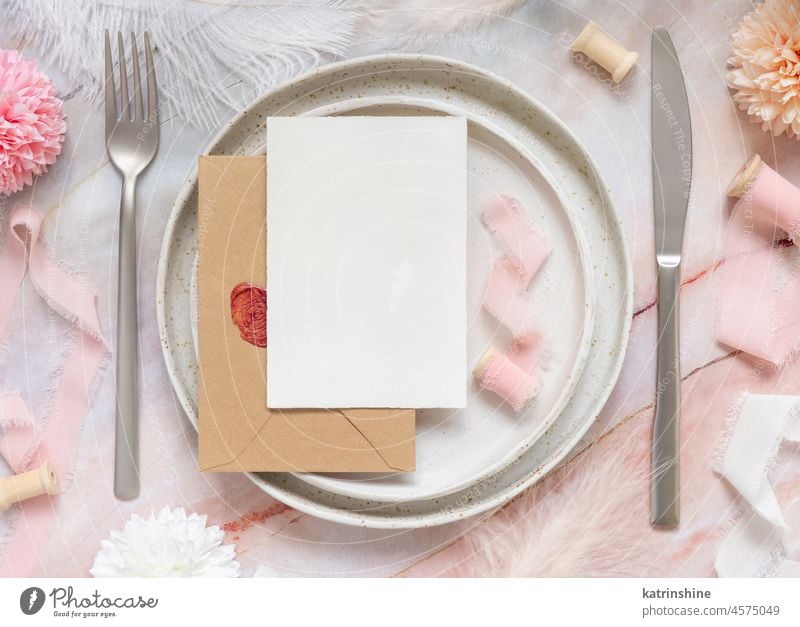 Wedding Table Platz mit einer Karte über Umschlag in der Nähe von Blumen, Seidenbänder und Federn, Mockup Postkarte Papier blanko rosa Tischplatz Kuvert