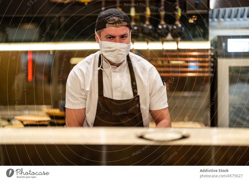 Koch in Uniform bei der Arbeit in der Restaurantküche Mann behüten vorbereiten professionell COVID Job Küche männlich Coronavirus neue Normale Bund 19