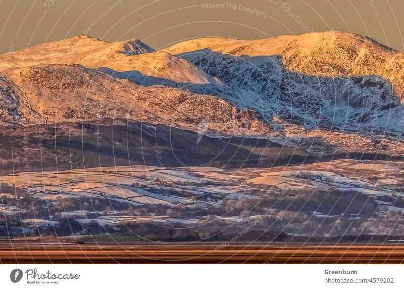 Letztes Licht auf Dow Crag, Coniston Old Man und Wetherlam, Blick über die Duddon-Mündung von Roanhead an der Cumbrian Coast. Schnee Winter Winterstimmung