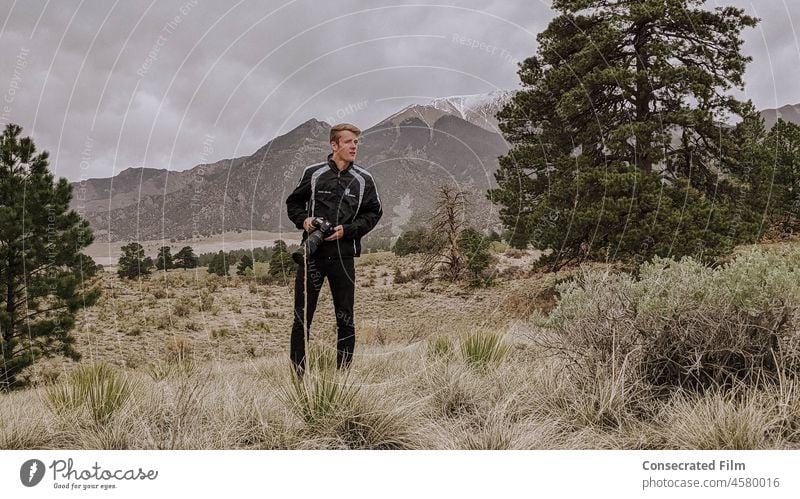 Mann geht im Wald mit Kamera spazieren und macht Fotos Fotograf Fotografie Fotografieren Fotokamera Himmel Berge Wolken reisen Abenteuer Abenteuer-Fotograf