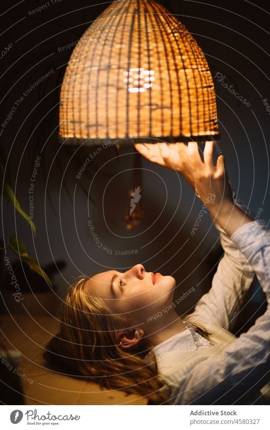 Junge Frau unter leuchtender Lampe eines Kronleuchters liegend Lügen glühen Licht berühren sinnlich Stil Abend sanft heimwärts elegant Windstille glänzend