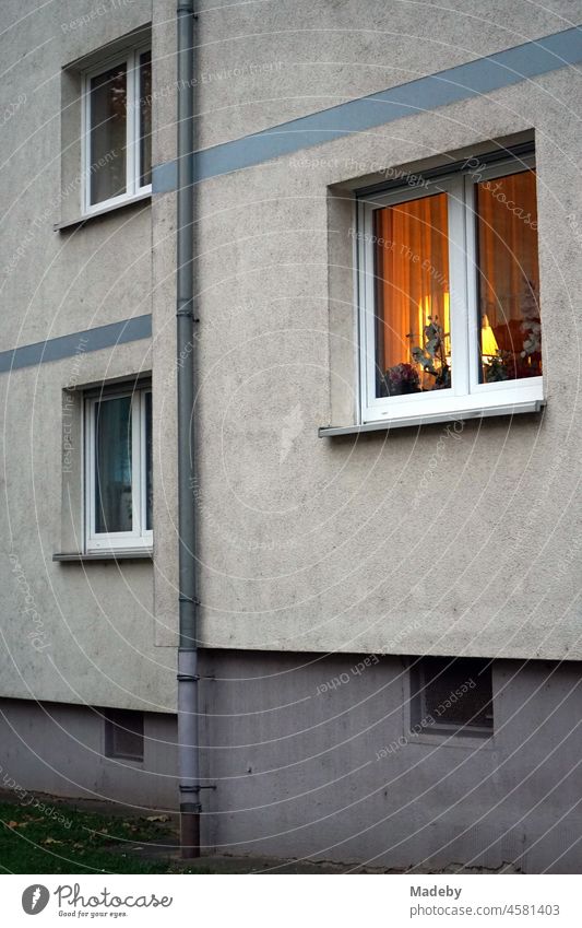 Blick durch die Gardine auf die Stehlampe in einem beleuchteten Wohnzimmer in einem Wohnblock der Sechziger Jahre an der Seckbacher Landstraße im Stadtteil Bornheim in Frankfurt am Main in Hessen