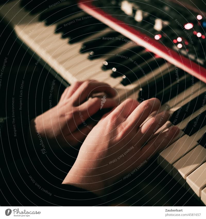 Mädchen spielt nachts auf rotem Keyboard, Hände auf der Tastatur Hand songwriting Tasten Knöpfe Regler Musik spielen Musik machen Musikinstrument Nahaufnahme