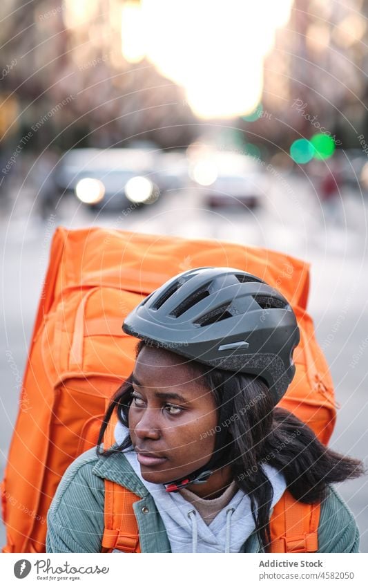 Schwarze Zustellerin auf dem Fahrrad Frau Versand Rucksack Dienst Orden Straße Reiter Mitfahrgelegenheit Fahrbahn Arbeit Thermo Gebäude Großstadt Afroamerikaner