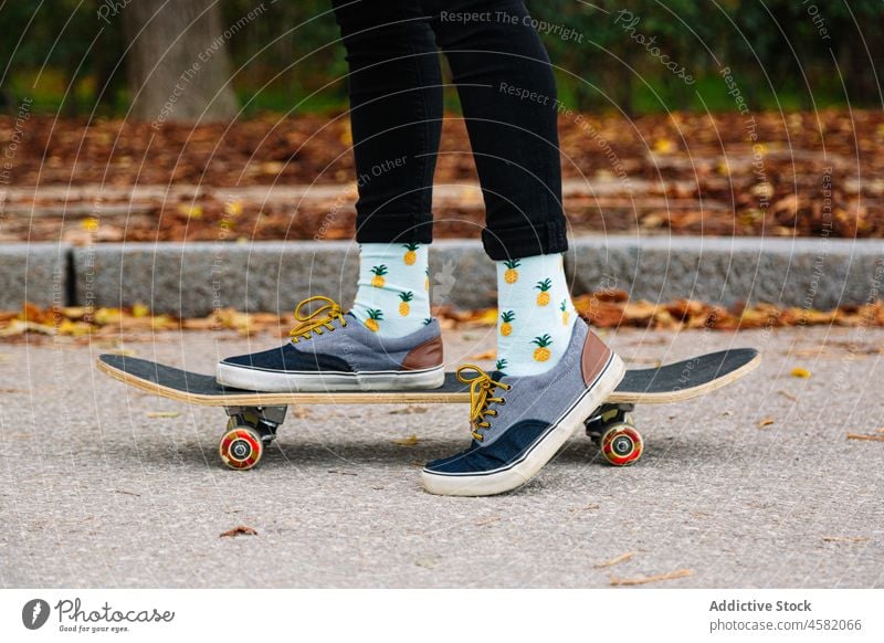 Crop Person in Turnschuhen auf Skateboard auf Asphalt Straße Skater Großstadt urban Straßenbelag lässig Jeanshose aktiv Aktivität Bein Freizeit Subkultur ruhen